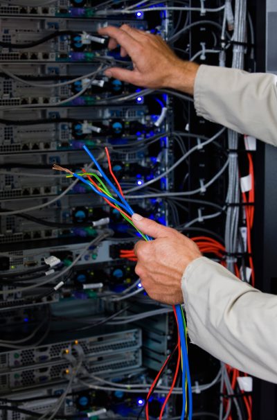 Close-up,Of,Computer,Technician,Holding,Colorful,Wires,In,Server,Room